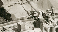 Brown filtered image of a factory next to sand heaps