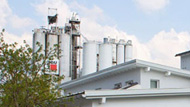 Tall factory with cylinder buildings showing the Baumit logo