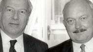black and white photo two men in suits with ties standing next to each other
