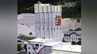 Tall grey factory building with a Baumit logo on the side